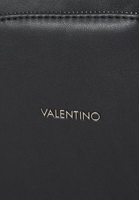 Black leather bag with smooth texture, featuring the embossed name "VALENTINO" in shiny silver. Minimalist design with no additional hardware.
