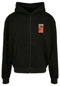 Černá mikina na zip vyrobená z měkkého materiálu, s přední kapsou a živě oranžovou nášivkou s textem "MÍR" a "ŽÁDNÁ VÁLKA" a květinovým vzorem.