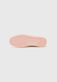 Sneaker sole with a textured pink rubber surface, featuring a honeycomb pattern and curved lines for added grip and flexibility.