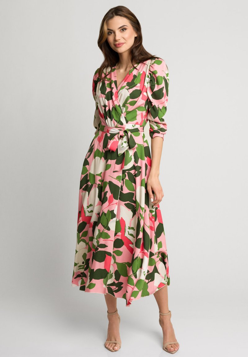 Sukienka w kwiaty z zielonymi, różowymi i białymi wzorami liści. Długie rękawy, ściśnięta talia z kokardą, lekko opadająca do długości midi. Gładki materiał.