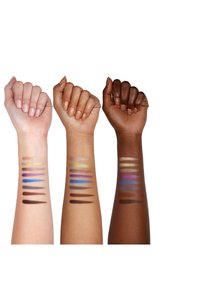 Tre arme med swatches af øjenskygge i forskellige farver: guld, blå, lilla og brun, på lys, medium og mørk hudtone.