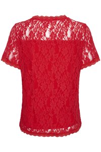 Haut en dentelle rouge avec un décolleté et des manches à bords festonnés, en tissu transparent à motifs floraux, et une finition légère et texturée.