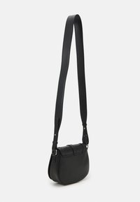 Černá kožená křížová taška zaobleného tvaru, s plochým vrškem, nastavitelným popruhem a prošíváním na předním víku.