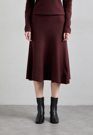 Rochie tricotată burgundy cu o fustă evazată, purtată cu cizme din piele negre până la gleznă. Rochia are mâneci lungi și un corset ajustat.