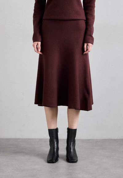 Burgundy knit dress with a flared hem paired with black leather ankle boots. Dress features long sleeves and a fitted bodice.