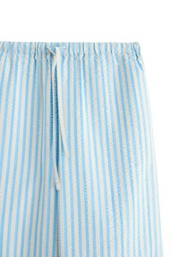 Ljust blå och vitrandig tygshorts med elastisk midja och dragsnöre. Strukturerad mönster med vertikala ränder och mjuk finish.