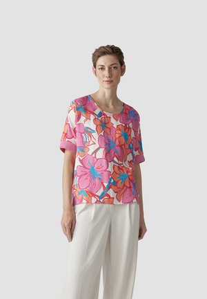 Blumige Bluse aus leichtem Stoff, mit pinken und orangenen Blumen und türkisfarbenen Akzenten. Kurzärmlig, runder Ausschnitt, leicht lockere Passform.