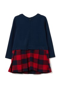 Marineblaues Langarmoberteil mit einem Reißverschluss auf der Rückseite, kombiniert mit einem rot und marineblauen karierter, plissierter Rock, der an der Taille befestigt ist.