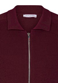 Maglione zip-up in magenta con una texture a coste, dotato di colletto ripiegato e una cerniera argentata con un accento rosso. Etichetta del marchio visibile all'interno.
