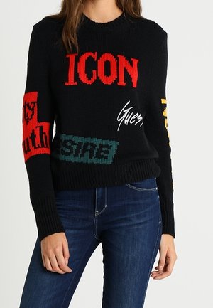 Maglione lavorato a maglia nero con grande testo multicolore, incluso "ICON" in rosso, e vari loghi in tonalità vivaci sulle maniche.