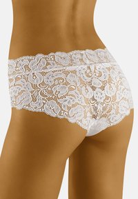 Slip hipster bianco in pizzo con motivo floreale, caratterizzati da una vita scalloppata e una texture trasparente. Vita elastica per una vestibilità e comfort ottimali.