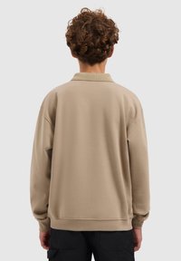 Beige lange mouwen pullover met kraag, voorzien van geribbelde manchetten en een gestructureerde stof. Eenvoudig ontwerp zonder zichtbare logo's of patronen.