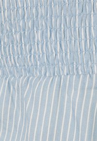 Ljust blått tyg med vertikala vita ränder och samlad, elastisk smockdetalj upptill.