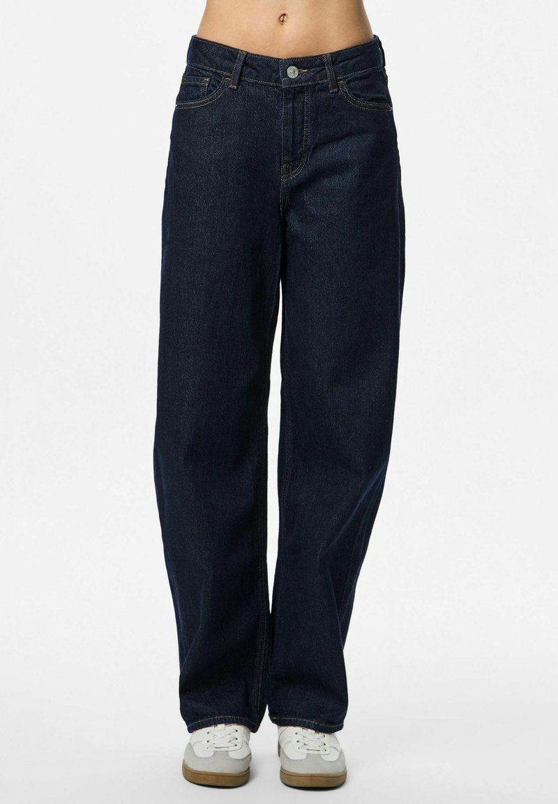 Klasiski tumši zili platā kāju džinsi ar piecām kabatām un smalku dzelteno šuvi. Pabeigti ar metalizētu pogu aizdari.