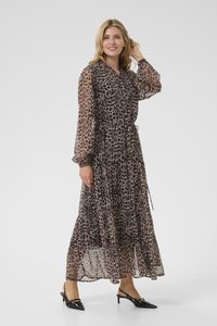Robe maxi en tissu brun transparent avec imprimé léopard noir, longues manches amples, taille cintrée et ourlet à volants superposés. Chaussures noires à talons.