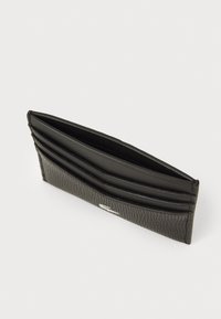 Sort læder kortholder med en struktureret finish, der har flere kortslots og en glat inderside. Kompakt og slankt design.