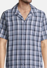 Chemise à manches courtes à carreaux bleus et gris, avec un devant boutonné, un col pointu et une poche poitrine unique. Tissu léger.