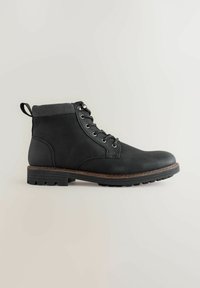 Zwarte enkelboot met een glad leren bovenwerk, ribbelstof kraag, metalen oogjes en een robuuste rubberen zool. Voorzien van een aantreklip aan de achterkant.