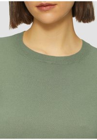 Oliwkowy sweter dzianinowy z okrągłym dekoltem. Tekstura jest gładka i lekko elastyczna, posiada prążkowane detale przy kołnierzu.
