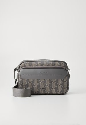 Bolso bandolera gris de Lacoste con patrón geométrico, bolsillo delantero con cremallera y correa ajustable sobre fondo blanco.