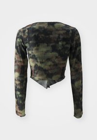 Dugi rukav cropped top s rebrastom teksturom, koji ima uzorak kamuflaže u tamnozelenim i crnim nijansama te dizajn s razdvojenim leđima.