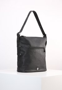 Zwarte leren schoudertas met een textuur oppervlak, verstelbare schouderriem, voorvak met rits en vierkante logo patch aan de onderkant.