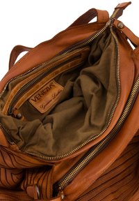 Intérieur d'un sac à main en cuir brun avec une doublure en tissu beige doux, comportant une poche zippée et une étiquette de marque embossée. Surface texturée avec des coutures.