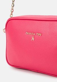 Różowa skórzana torebka o teksturowanej powierzchni, prostokątnym kształcie, logo w złotym odcieniu i łańcuszkowym pasku na ramię.