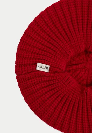 Red knitted beret with ribbed texture and small white label displaying the brand name "GOBI" on a plain background.