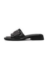 Sandalia de cuero negro deslizable con una correa ancha que presenta una hebilla metálica. Tacón bajo, textura suave y diseño minimalista.