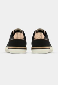 Schwarze Sneakers mit glatter Textur, einem Akzent in Roségold an der Ferse, weißer Gummisohle und minimalistischem Design.