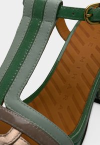 Πράσινο δερμάτινο σανδάλι με λουριά και μεταλλικό καφέ λεπτομέρεια, με υφή ταμπά εσωτερική σόλα και χρυσή αγκράφα.