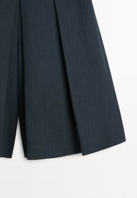 Jupe ou vêtement en tissu plissé gris foncé avec des plis nets définis, présenté sur fond blanc.