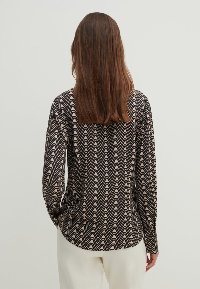 Langärmliges Hemd in Creme und Schwarz mit einem Zickzack-Muster, mit rundem Ausschnitt und einer leicht taillierten Silhouette.