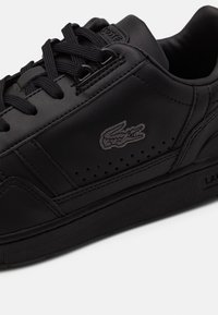 Sneaker in pelle nera con superficie testurizzata, punta arrotondata, perforazioni e logo ricamato tono su tono. Lacci piatti neri e suola in gomma.