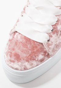 Baskets en velours rose avec lacets en satin blanc, surface texturée et semelle en caoutchouc. Bout arrondi et design à plateforme surélevée.