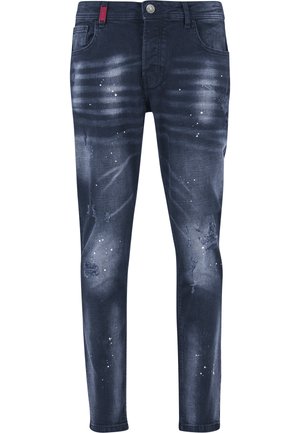 Mørkeblå slim-fit jeans med falmede områder, malingssprut, og slitte partier, med frontlommer og metallknapp.