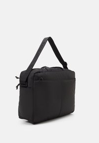 Black padded messenger bag, rectangular shape, features a prominent strap with logo, zip closure, and side handle for carrying convenience.
