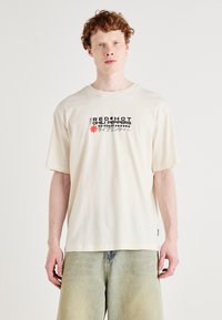 Elfenbensfarvet bomulds t-shirt med korte ærmer, der viser et grafisk print af "Red Hot Chili Peppers" og et rødt stjernesymbol på forsiden.