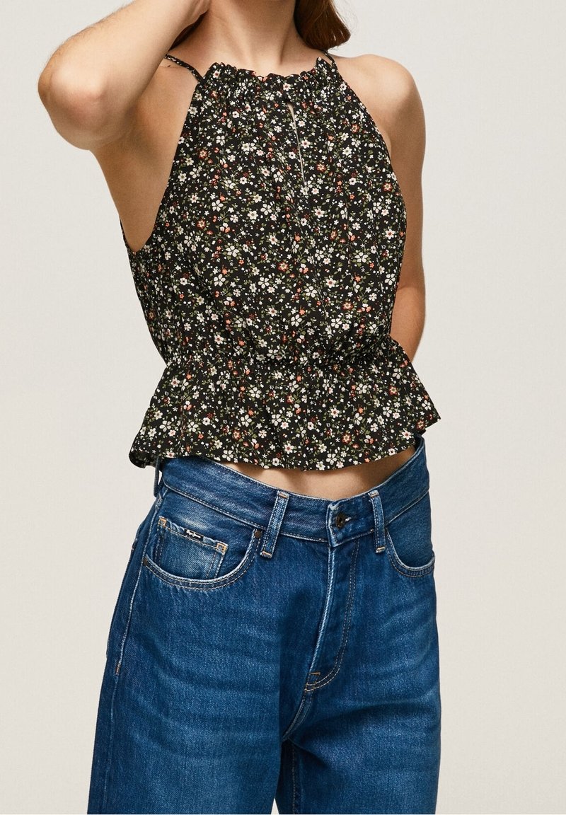 Czarna bluzka peplum w kwiaty z marszczonym dekoltem, zdobiona białymi, różowymi i zielonymi kwiatami. W połączeniu z niebieskimi, wysokimi dżinsami.