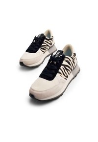 Zapatillas con una mezcla de tejido de estampado de cebra negro y blanco, detalles en ante crema, cordones negros y una suela ligera gris.