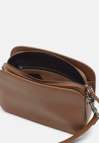 Borsa a tracolla in pelle marrone con una texture liscia, doppie tasche con zip, tracolla regolabile e logo impresso sul davanti.