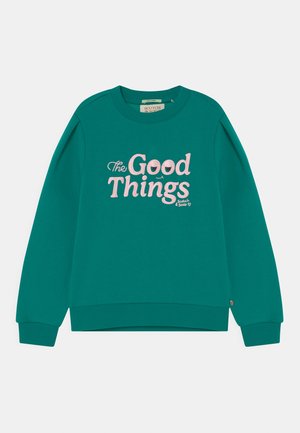 Türkisfarbener Pullover mit langen Ärmeln und pink gesticktem Text "The Good Things" sowie kleinem "Scotch & Soda" Logo in der Mitte vorne.