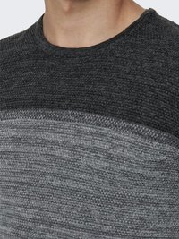 Suéter de lana gris con un patrón texturizado, que presenta un cuello redondo y un degradado de gris oscuro a gris claro a lo largo del pecho.