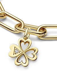 Collana in oro con pendente a trifoglio caratterizzato da foglie a forma di cuore, un accento di diamante e un'apertura triangolare al centro.