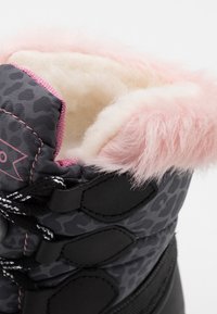 Botte mi-mollet noire et grise avec un motif léopard. Doublure en fausse fourrure rose douce sur le revers et accents en métal noir.