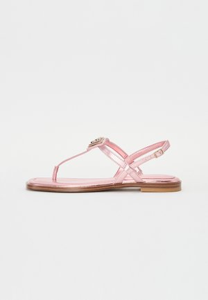 Sandali piatti metallici rosa con design a t-strap, cinturini incrociati alla caviglia e dettaglio decorativo con fibbia. Suola piatta in legno.