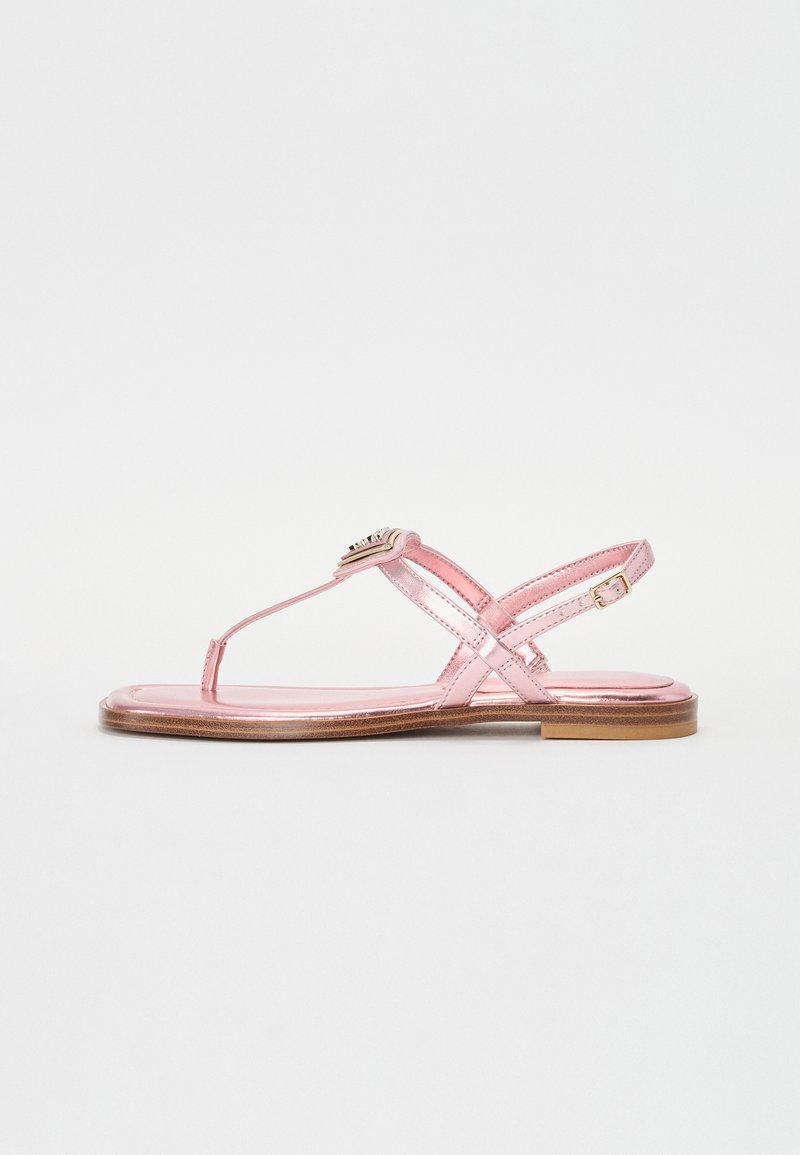 Pink metallic flat sandals with a t-strap design, cross-over ankle straps, and a decorative buckle detail. Flat wooden sole.