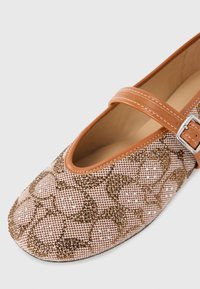 Tan Mary Jane shoe with a beaded, geometric pattern in shades of pink and brown, featuring a single leather strap with a silver buckle.