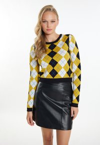 Maglione a costine giallo, nero e blu con motivo argyle, maniche lunghe e orlo nero a coste, abbinato a una minigonna nera in pelle.